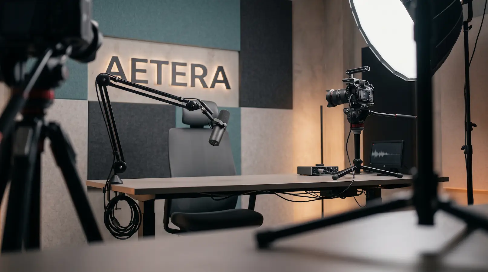 A calm Aetera creator studio with a camera, broadcast microphone, and AETERA wall sign